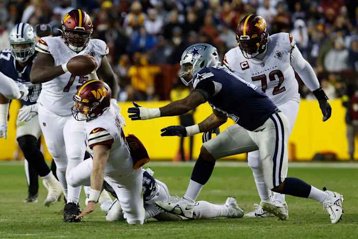 Sam Williams reaches for the Washington Commanders’ quarterback who is falling to the ground with the ball in one hand